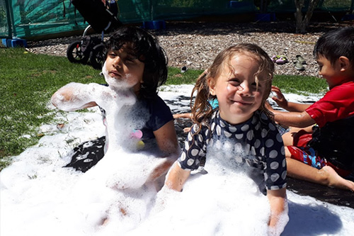 Kids playing in bubbles at a community play day